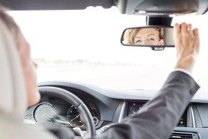 Reflection in rear view mirror of businesswoman driving car
